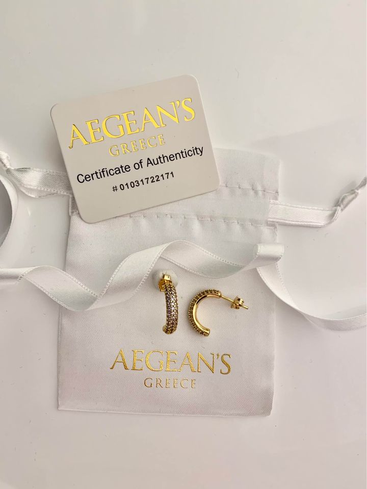 Close-up of prong-set round white cubic zirconia stones on 18K gold-plated Italian brass hoop earrings